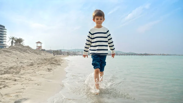 Menino Sorridente Feliz Suéter Andando Praia Areia Salpicando Água Com — Fotografia de Stock