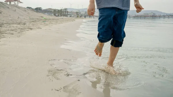 Młody Chłopiec Biegający Boso Piaszczystej Plaży Cieszący Się Zimną Wodą — Zdjęcie stockowe