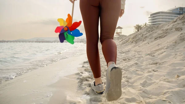Powolny Ruch Młodej Kobiety Trzymającej Kolorowy Wiatrak Spacerujący Piaszczystej Plaży — Zdjęcie stockowe