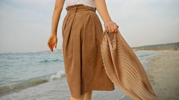 Fechar Uma Mulher Andando Uma Praia Areia Dia Ventoso Segurando — Fotografia de Stock