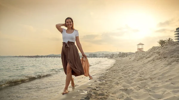 日落时分 穿着长裙在沙滩上散步的快乐微笑的女人 旅游和假日的概念 — 图库照片