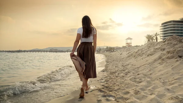 在刮风的日子里 一个女人拿着丝巾在沙滩上散步 暑假的美丽与祥和 — 图库照片