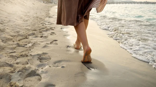 日没時に砂浜を歩く長いスカートの中の女性の裸の足の閉鎖 — ストック写真