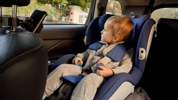 蹒跚学步的小男孩骑着车 从开着的窗户往外看 儿童旅行 婴儿安全 儿童乘车旅行的概念 — 图库照片