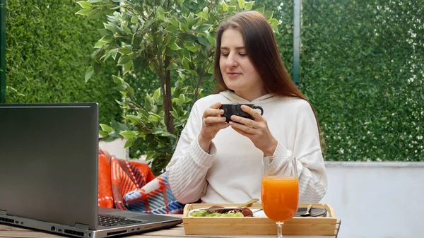 Genç Esmer Kadın Çay Içiyor Yaz Terasında Dizüstü Bilgisayarla Çalışıyor — Stok fotoğraf
