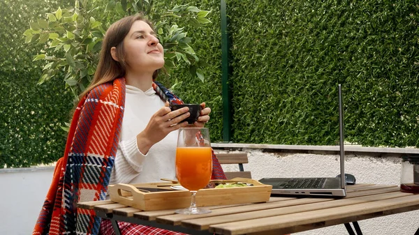 若い女性が屋外テラスでノートパソコンで仕事をしてコーヒーを飲んでいた フリーランスの概念は リモートジョブから 屋外で食事を働く — ストック写真