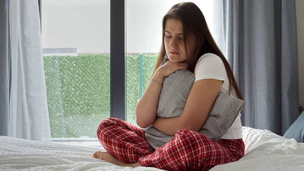 パジャマ姿の若い女性はベッドの上に群がり クッションを持って座り心地の良さを受け入れていました 悲しみ 感情的苦痛 ストレスという概念 — ストック写真