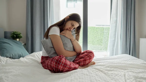 Genç Kadının Ağlamaktan Gözleri Kıpkırmızı Yatağa Oturmuş Sıkıca Sarılmış Bir — Stok fotoğraf