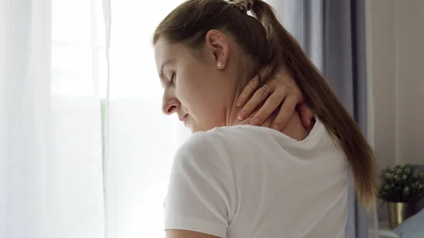 Mujer Joven Sentada Dormitorio Frotando Masajeando Dolor Cuello Espalda Concepto —  Fotos de Stock