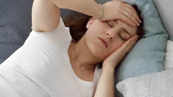 疲倦或紧张的女人躺在床上头痛的画像 — 图库照片