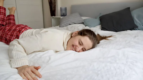 笑容满面的女人穿着睡衣躺在床上 在漫长的一天之后回到家的喜悦 知道你有一个舒适舒适的床可以躺在里面 — 图库照片