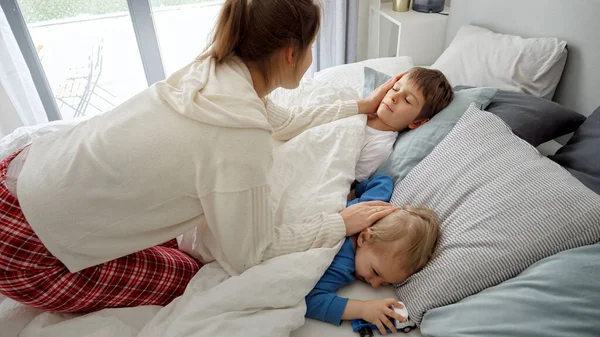 Jovem Mãe Amorosa Acariciando Seus Dois Filhos Dormindo Cama Manhã — Fotografia de Stock