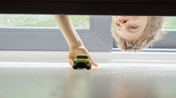 Mały Chłopiec Szuka Zabiera Swój Zabawkowy Samochód Zgubiony Pod Łóżkiem — Zdjęcie stockowe