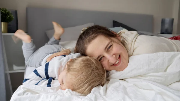 엄마가 귀여운 침대에 집에서 휴식을 취하는 침대에서 재미를 느끼는 부모와 — 스톡 사진