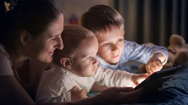 Retrato Menino Usando Tablet Computador Com Irmão Mãe Cama Noite — Fotografia de Stock