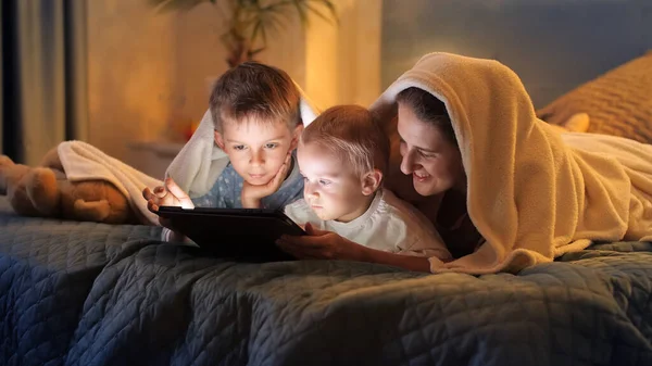 Два Мальчика Пижаме Развлекаются Матерью Постели Играют Игры Планшетном Компьютере — стоковое фото