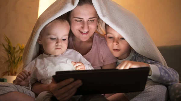 Jovem Mãe Com Dois Filhos Cobrindo Sob Cobertor Assistindo Vídeo — Fotografia de Stock