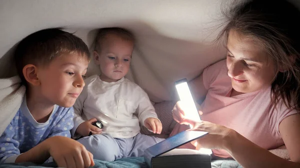 Два Мальчика Читают Книгу Матерью Лежа Ночью Одеялом Семья Проводящая — стоковое фото