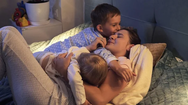 Два Любящих Мальчика Пижаме Обнимают Целуют Мать Лежащую Ночью Постели — стоковое фото