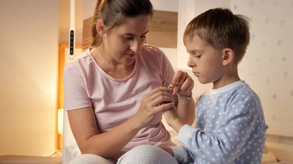 Ung Omtänksam Mor Skära Fingernaglar Till Sin Son Bär Pyjamas — Stockfoto