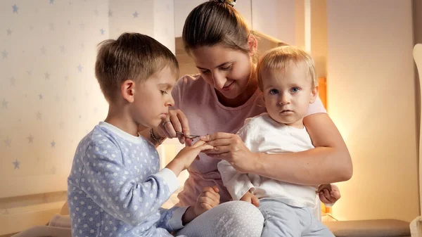 Mosolygó Anya Körmöket Vág Két Fiának Pizsamában Éjszaka Szülői Gyermekhigiénia — Stock Fotó