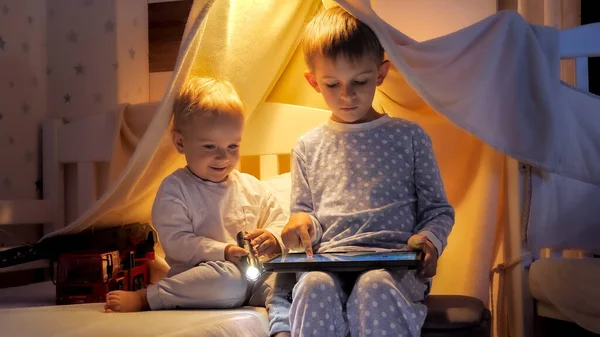 Dwóch Chłopców Piżamie Bawiących Się Nocy Łóżku Korzystających Tabletu — Zdjęcie stockowe