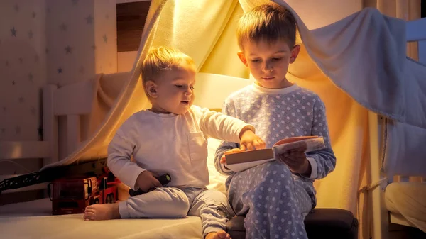 Старший Мальчик Читает Книгу Своему Младшему Брату Палатке Спальне Дети — стоковое фото