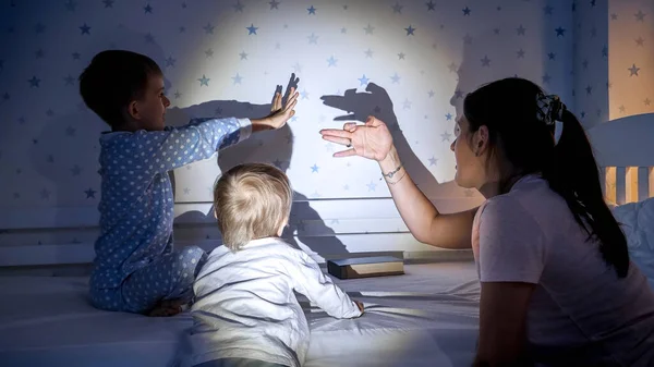 Glada Barn Med Mamma Leker Med Skuggor Från Ficklampan Väggen — Stockfoto