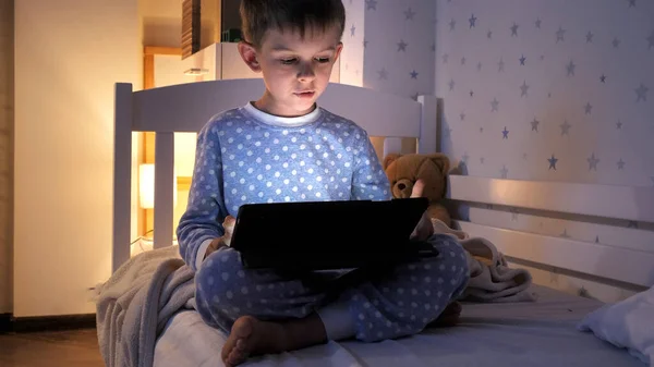 小男孩晚上在卧室里用平板电脑 儿童教育 儿童使用小玩艺儿保密 — 图库照片