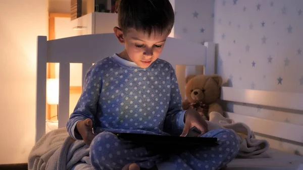 穿着睡衣的小男孩晚上在平板电脑上玩电子游戏 儿童教育 儿童使用小玩艺儿保密 — 图库照片