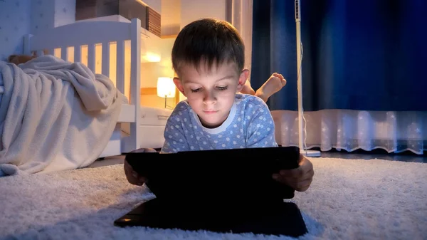 穿着睡衣的可爱男孩躺在房间的地板上 睡觉前使用平板电脑 儿童教育 儿童使用小玩艺儿保密 — 图库照片
