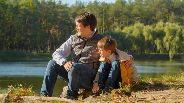 Niño Sentado Con Padre Lago Mirando Atardecer Sobre Bosque Familia — Foto de Stock