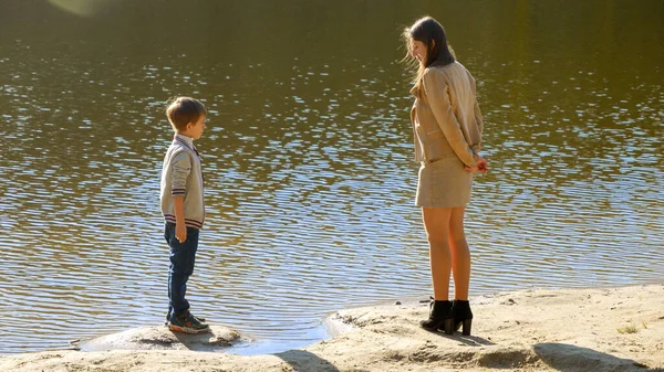 年轻美丽的母亲和儿子站在河岸上聊天 户外家庭 快乐的养育和童年 秋天的风景 孩子和父母在外面放松 — 图库照片