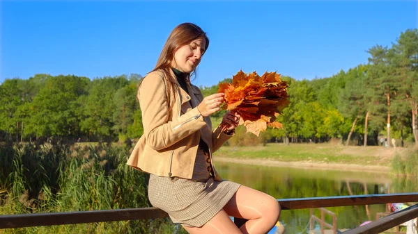 Schöne Lächelnde Frau Die Fluss Sitzt Und Auf Gelbe Herbstblätter — Stockfoto