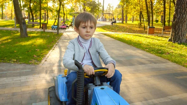 Portret Skoncentrowanego Chłopca Prowadzącego Traktor Dla Dzieci Jesiennym Parku Dzieci — Zdjęcie stockowe