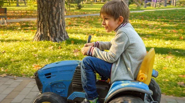 Retrato Niño Sonriente Alegre Divirtiéndose Parque Mientras Conduce Tractor Juguete — Foto de Stock
