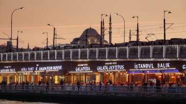 15 Mart 2023, Türkiye, İstanbul. Balıkçı ve restoranlar gün batımında ünlü Galata köprüsünde..