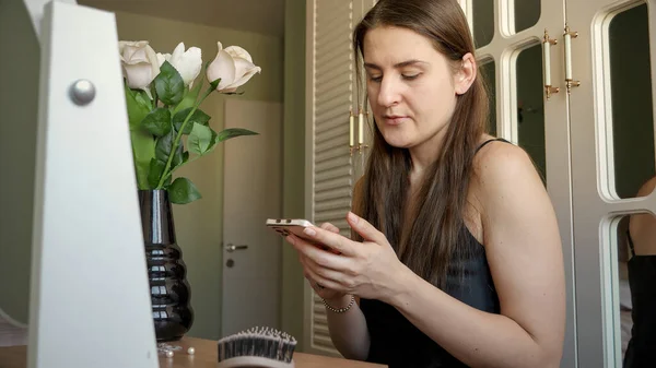 Genç Esmer Kadın Makyaj Masasında Oturuyor Akıllı Telefon Kullanıyor — Stok fotoğraf