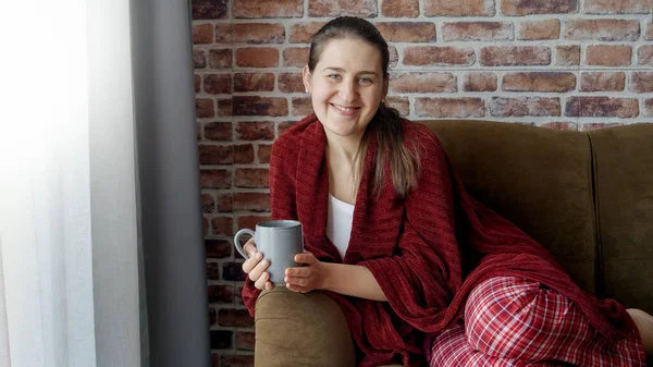 Vrolijk Lachende Vrouw Pyjama Bedekt Met Ruitjes Thee Drinkend Bank — Stockfoto