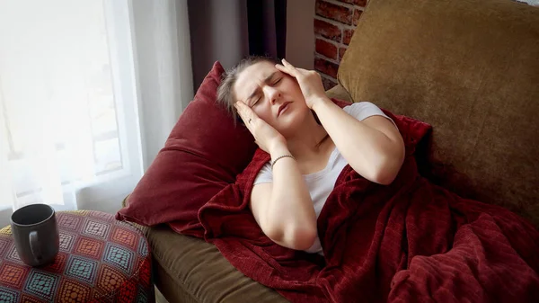 Mujer Joven Enferma Que Tiene Temperatura Acostada Sofá Tocándose Frente —  Fotos de Stock
