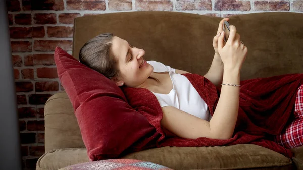 Joven Mujer Sonriente Descansando Sofá Sala Estar Utilizando Teléfono Inteligente — Foto de Stock