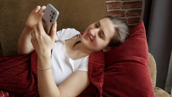 Улыбающаяся Женщина Лежит Диване Просматривает Интернет Смартфоне Люди Отдыхают Дома — стоковое фото