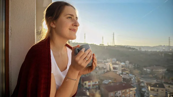Portret Uśmiechniętej Kobiety Trzymającej Filiżankę Herbaty Patrzącej Miasto Balkonu Ludzie — Zdjęcie stockowe