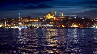 İstanbul, Türkiye - Şubat 2023: Boğazdaki sakin deniz dalgaları Ayasofya Camii 'ni ve aydınlatılmış sahil restoranlarını yansıtıyor.