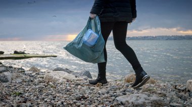 Plaj temizleme kampanyasına katılan genç bir kadın, plastik bir torbada çöp toplama ve çevrenin korunmasına katkıda bulunma