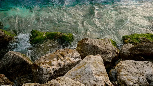天然海洋背景的特点是海浪缓慢地滚上布满海藻和海藻的岩石海滩 — 图库照片