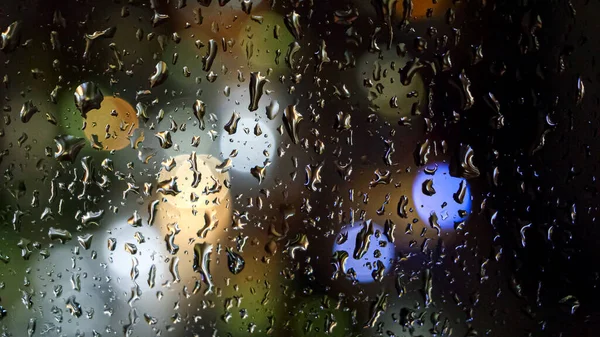 Zbliżenie Kropel Deszczu Strumieni Spływających Nocy Przez Okno Kolorowe Światła — Zdjęcie stockowe