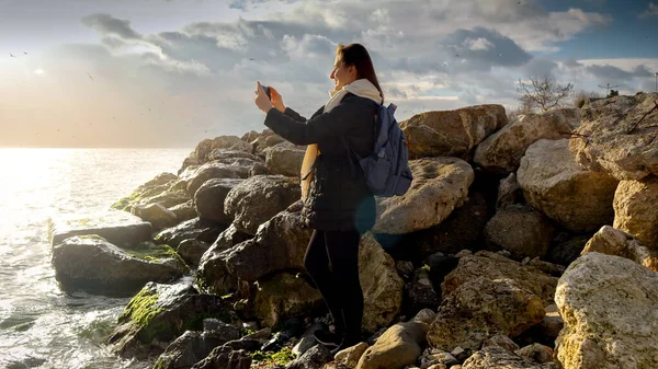 Kaunis Nuori Nainen Seisoo Kallioilla Rannikolla Tekee Valokuvia Kylmistä Meren — kuvapankkivalokuva