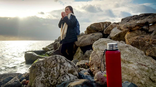 Jonge Vrouw Ontspannen Aan Rotsachtige Zeekust Bij Zonsondergang Het Drinken — Stockfoto