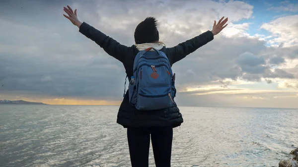 Жінка Рюкзаком Стоїть Морській Скелі Дивлячись Холодні Океанічні Хвилі Простягнутими — стокове фото